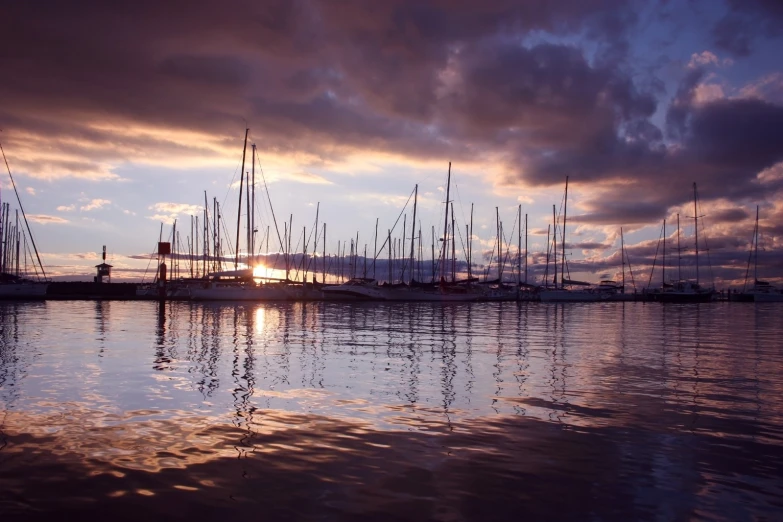 a group of sailboats in the water with a cloudy sky