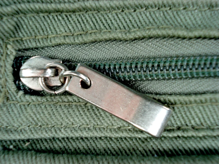 close up view of the zipper of green colored uniform material