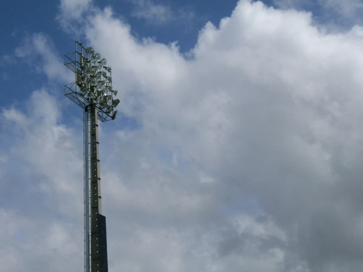 a cell tower with a cloud filled sky in the background