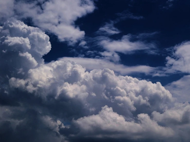 a jet airplane flies across the blue sky with many clouds