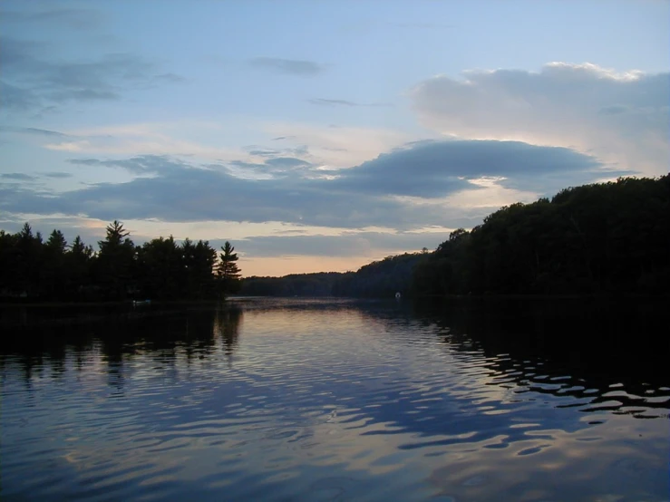 the sun is just starting to set over the trees on this lake