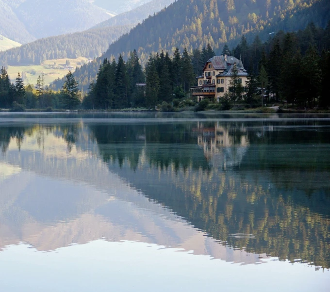 a view of a house by a lake and some mountains