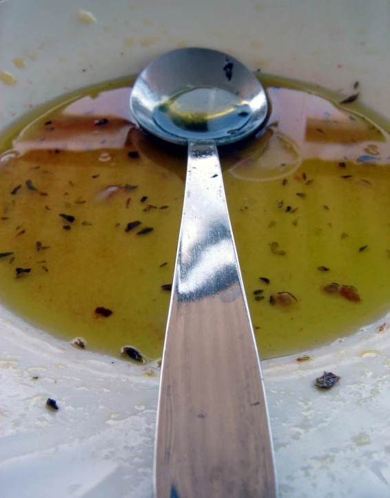 a spoon with liquid in it is laying next to a bowl