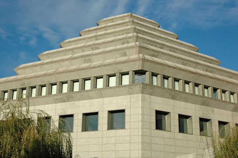 a concrete building with several windows, trees and bushes