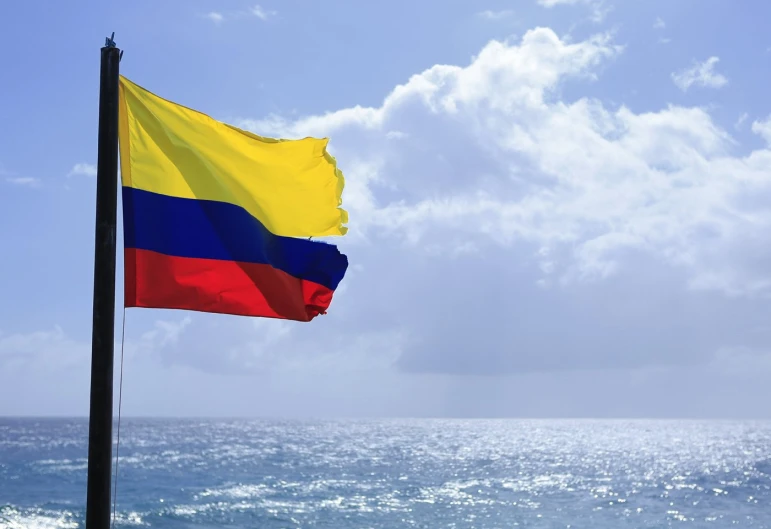 a flag flying over the ocean under a blue sky