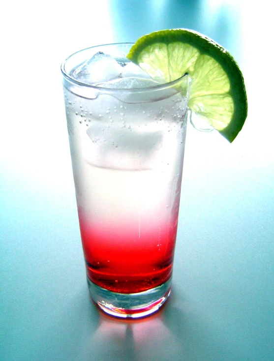 there is a small glass with some liquid and a lime wedge on top