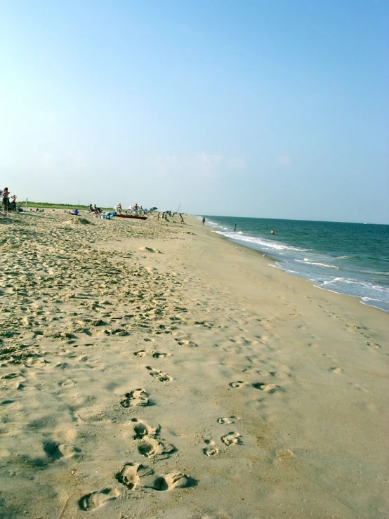 a sandy beach with people walking in the sand