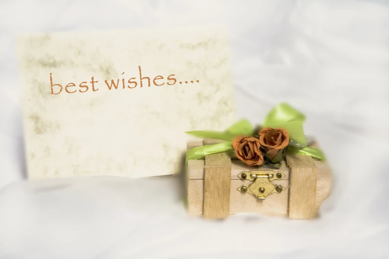 a card sits atop a wooden trunk on a white blanket