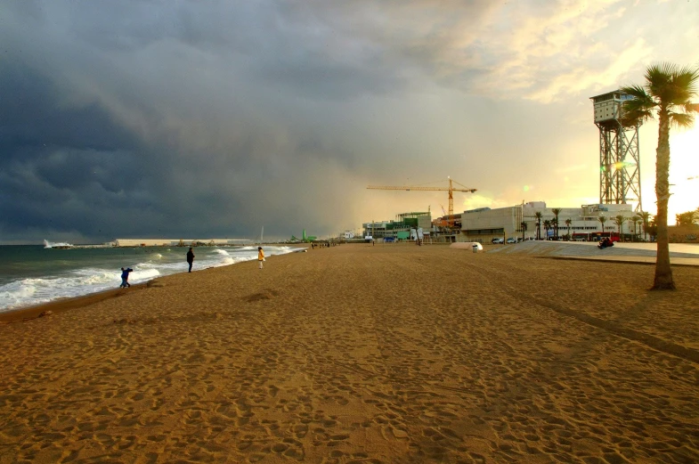 a beach and boardwalk under a cloudy sky with palm trees