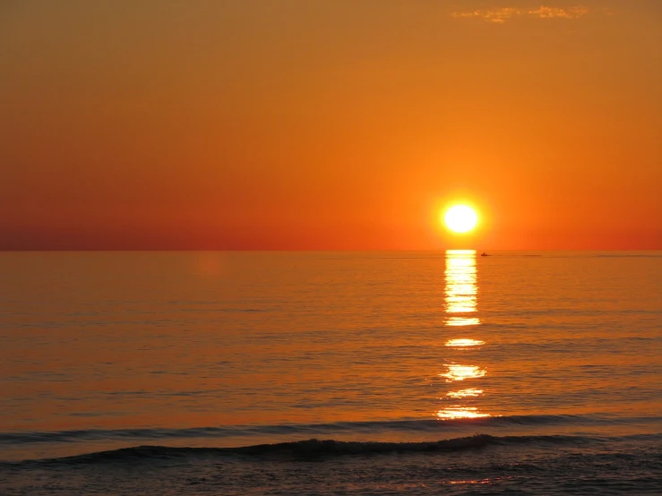 the sun is setting over the ocean as the tide rolls in