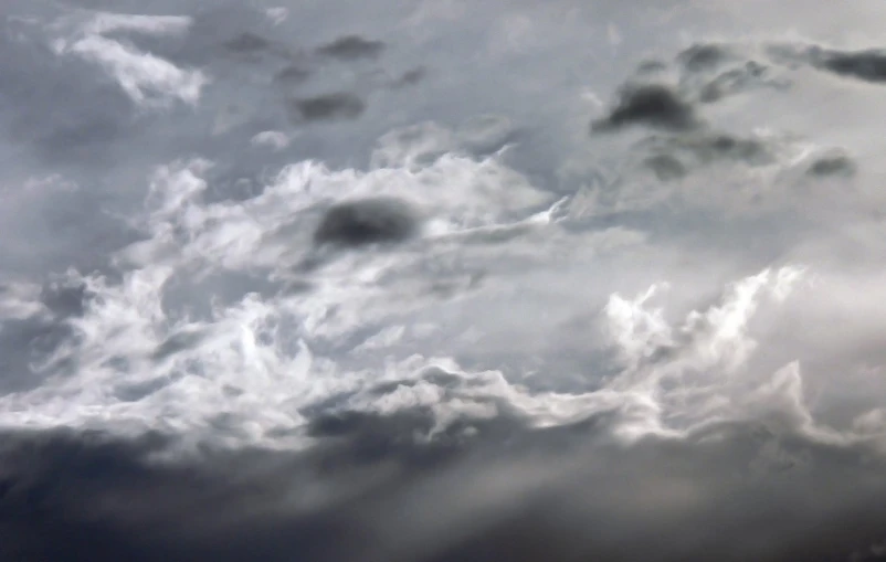 a plane flying through a cloudy sky above a tree line