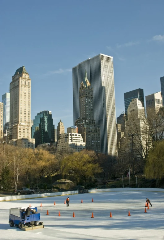 people are ice skating in front of large buildings