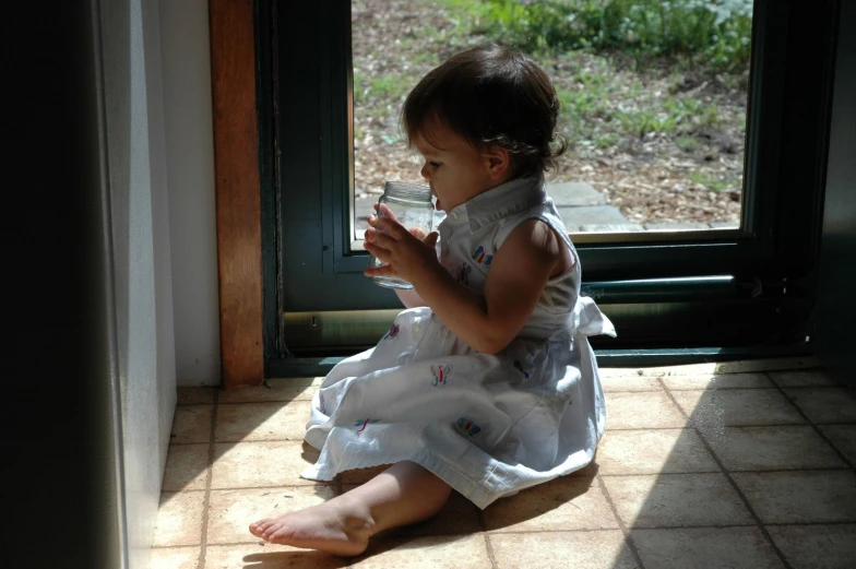 a small girl sitting on the ground by a door