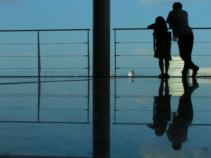 a silhouette of a mother and her daughters standing in a balcony overlooking the ocean