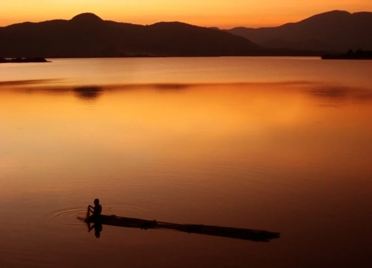 two people on a boat with hills in the background