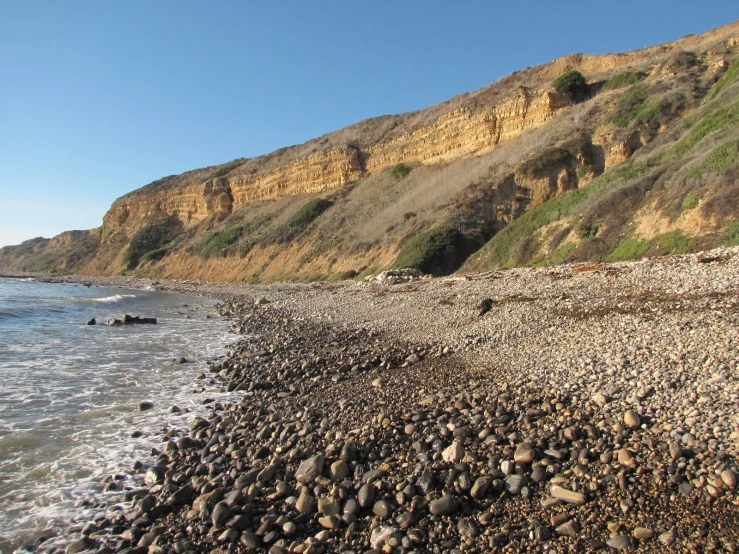 rocky beach with sea cliffing near shore on sunny day