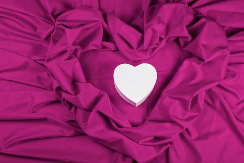 heart - shaped piece of paper on a bright pink fabric
