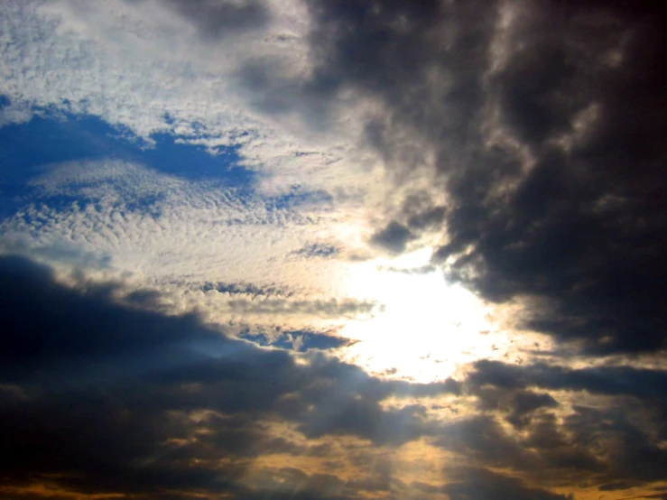 some clouds in the sky with sun glaring through