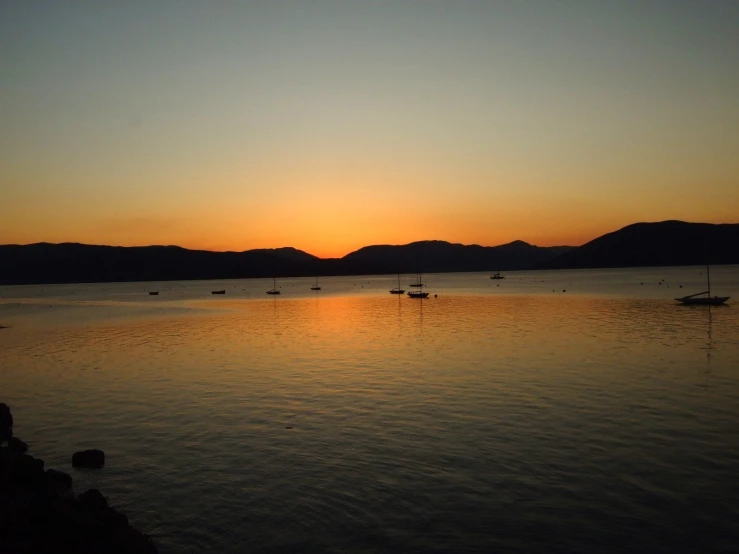 a po of the sunset over a lake and mountains