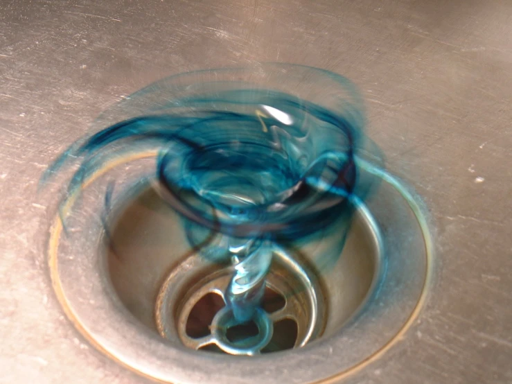 a drain in a kitchen sink with blue swirling ink