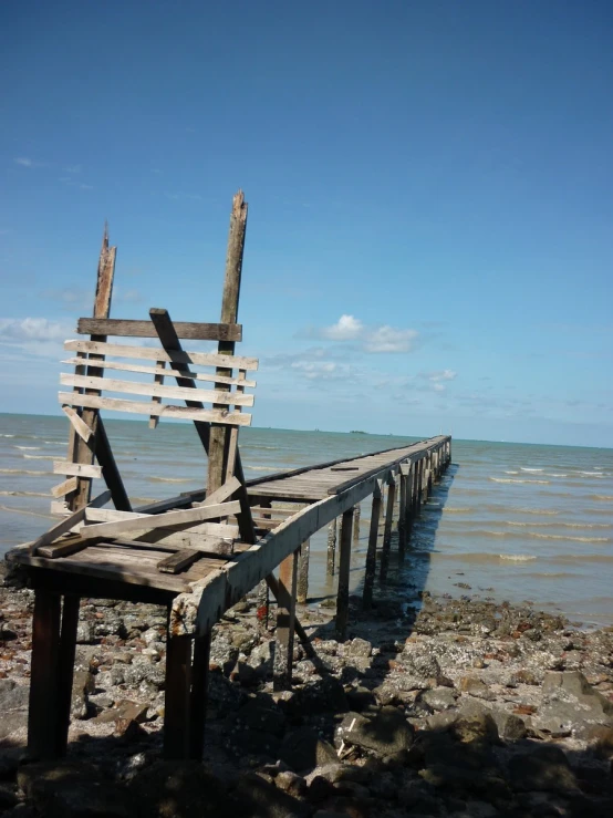 a wooden bench sitting on top of rocks near the ocean