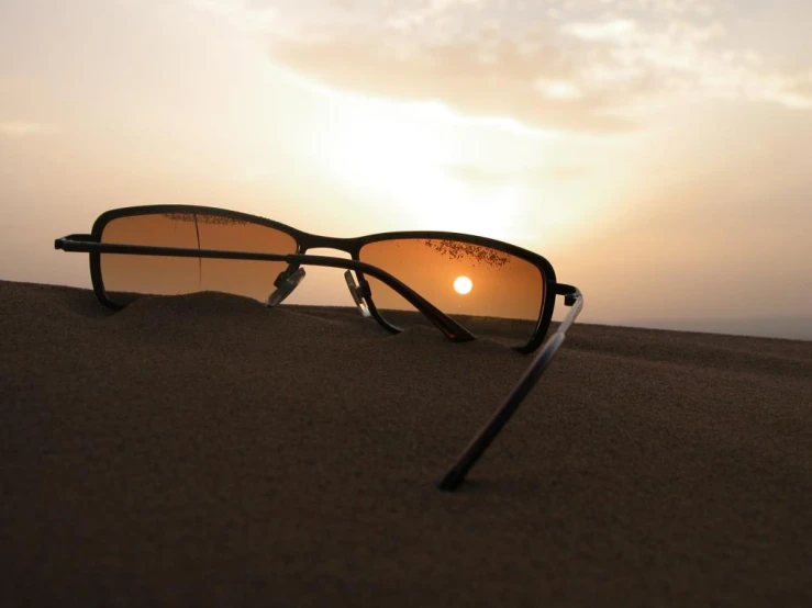 the sun reflects off of the reflection of sunglasses on a sand dune