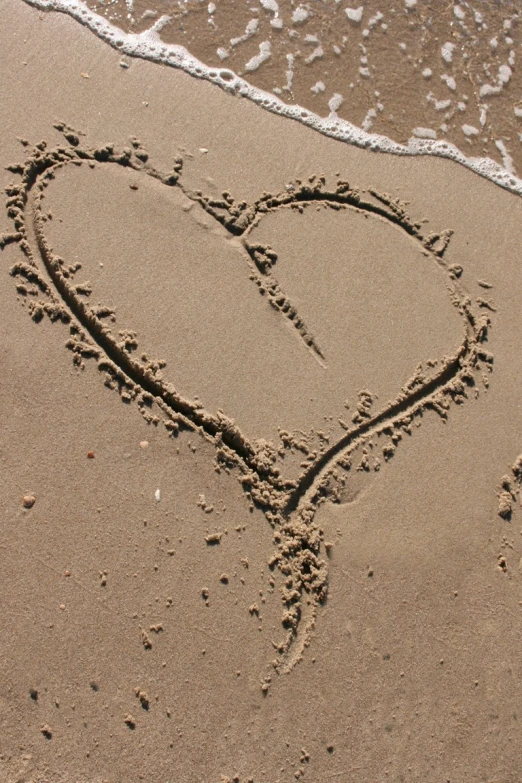 a heart drawn in the sand on the beach