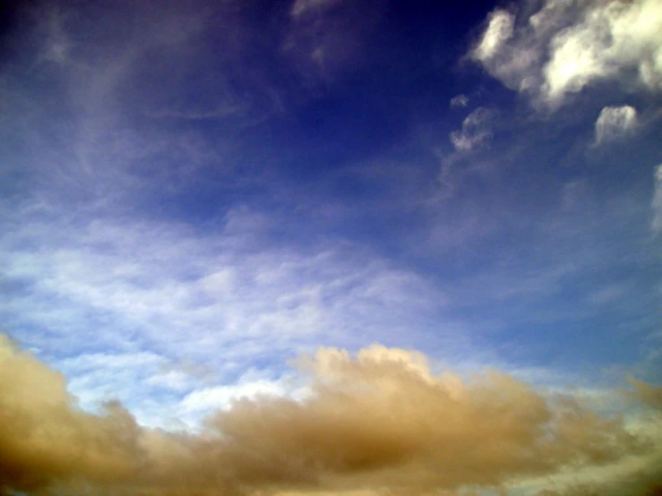 a plane in the air with clouds above it