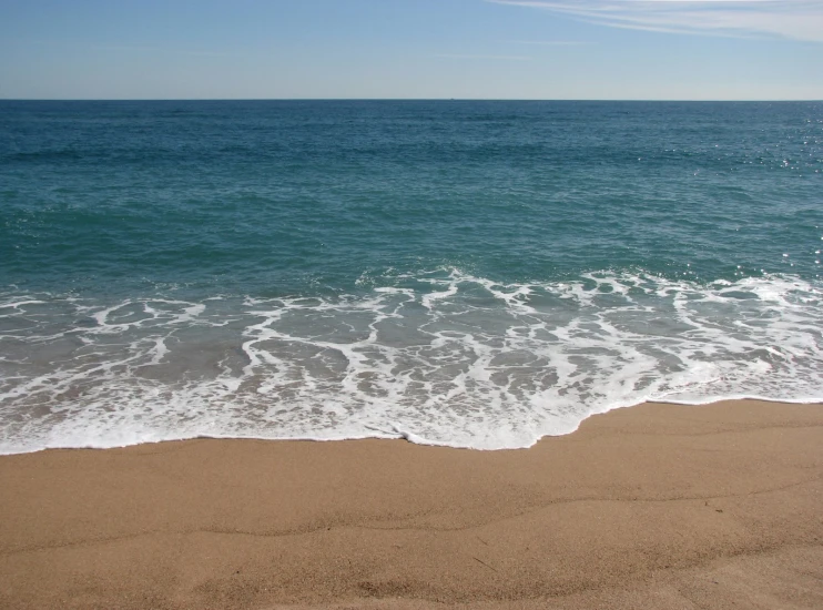 a beach with foamy water and the shoreline