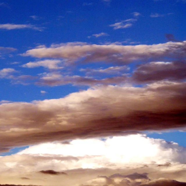 white fluffy clouds in the blue sky as seen from a hillside