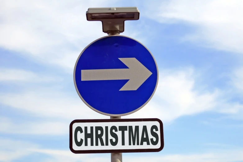 a street sign shows that the direction of christmas is on a pole