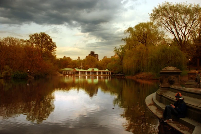 a person sitting near the water with trees in the background