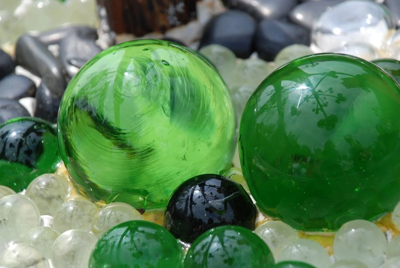 three green and black glass balls surrounded by beads