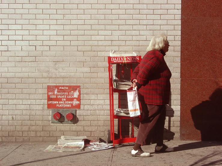 an older lady is walking by a public pay phone