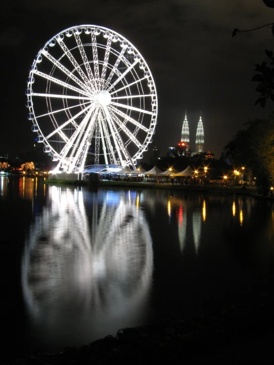 a ferris wheel reflected in the water at night