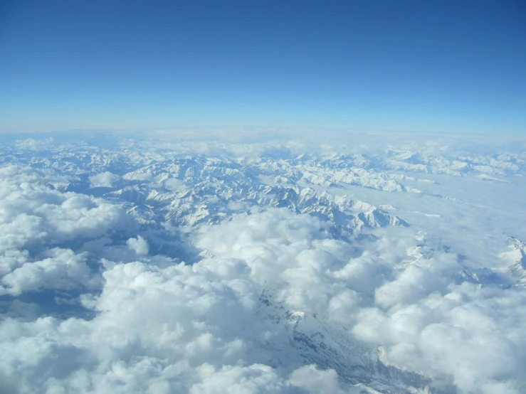 white clouds and blue sky over a mountainside