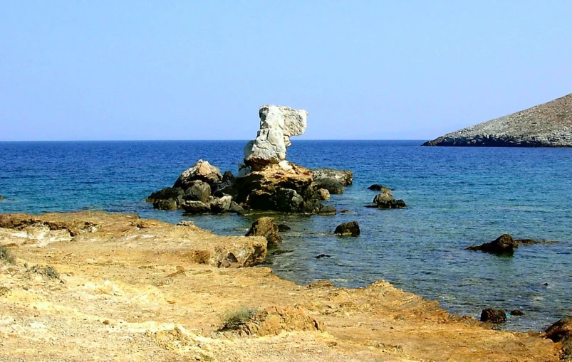 a beach area next to the ocean with a stone rock formation