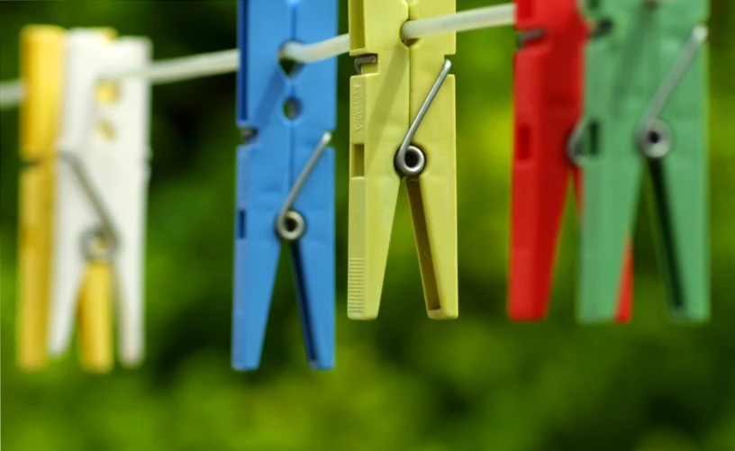 colorful clothes pegs hanging on a wire with a string