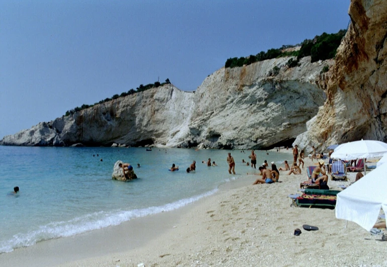 a crowded beach has white umbrellas and chairs