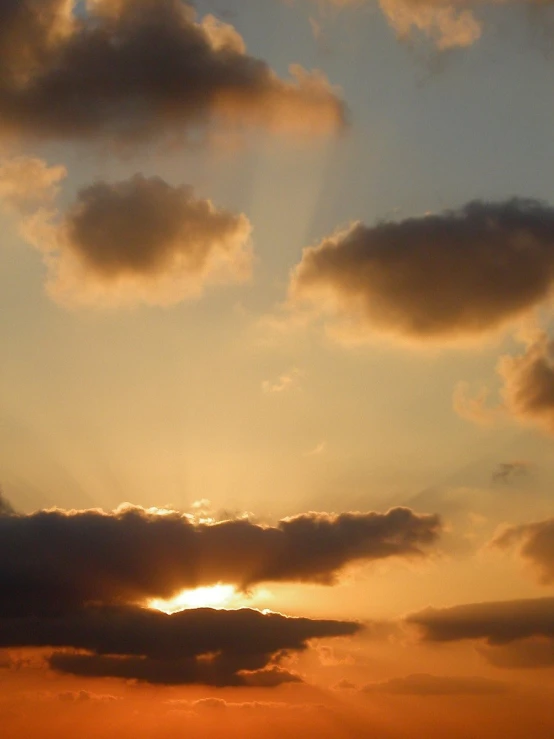 the silhouettes of clouds above the water at sunset