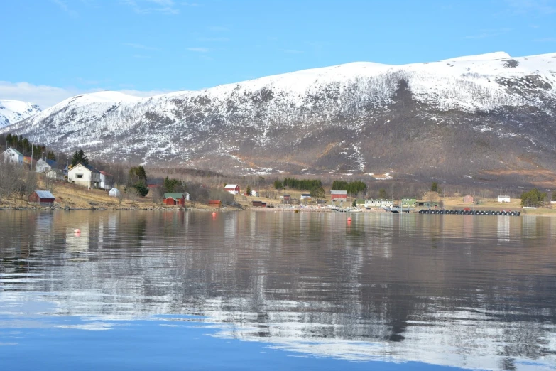 a lake with snow on the mountains behind it