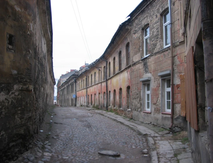 a small old city street with an abandoned building in the background