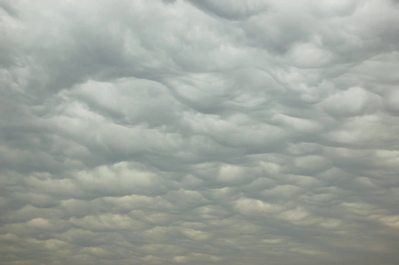 a plane flies through the cloudy sky in an open field