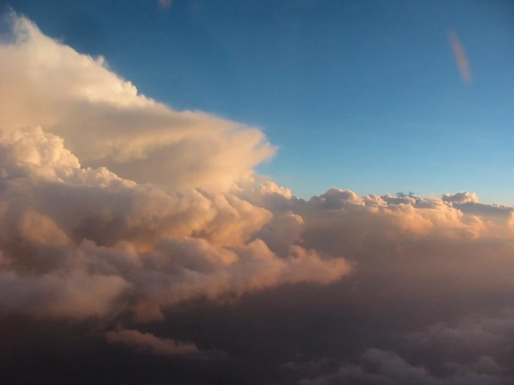 view from an airplane in the clouds towards a setting sun