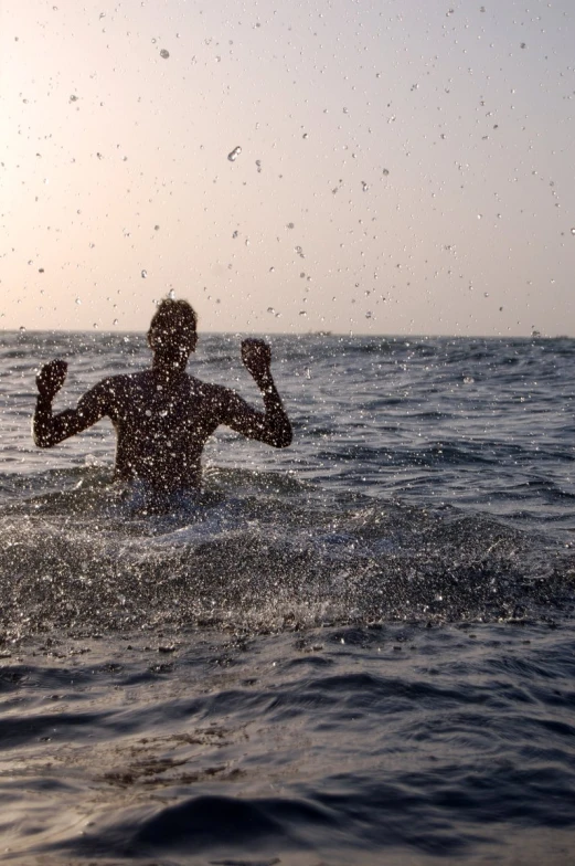 a man wading in the ocean with his arms out