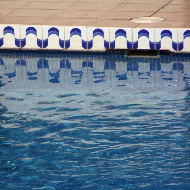 a long row of blue and white tiles by a pool
