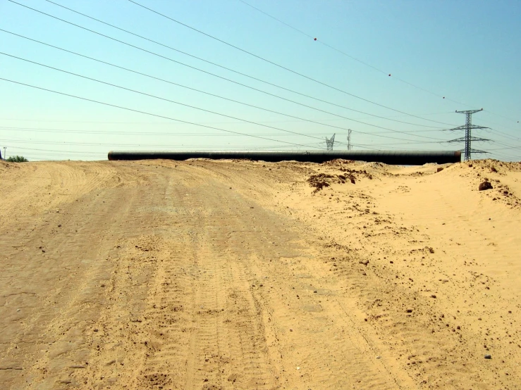 an empty dirt road with telephone poles on it