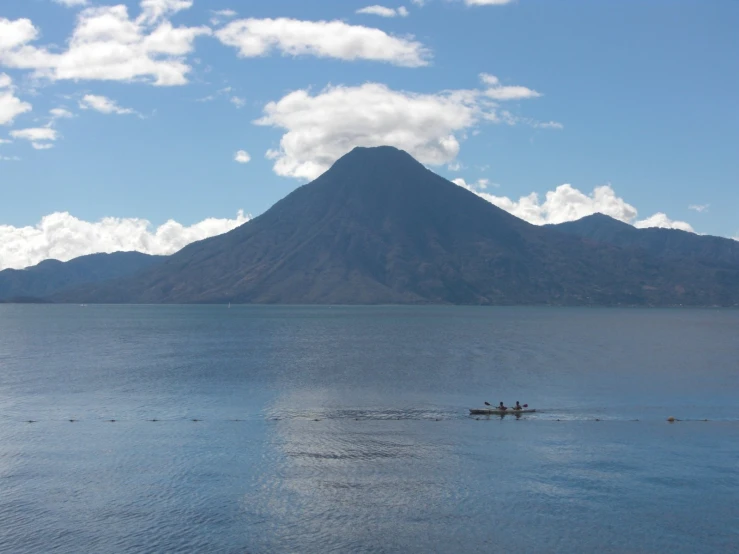 a mountain looms in the background as two boats travel through water