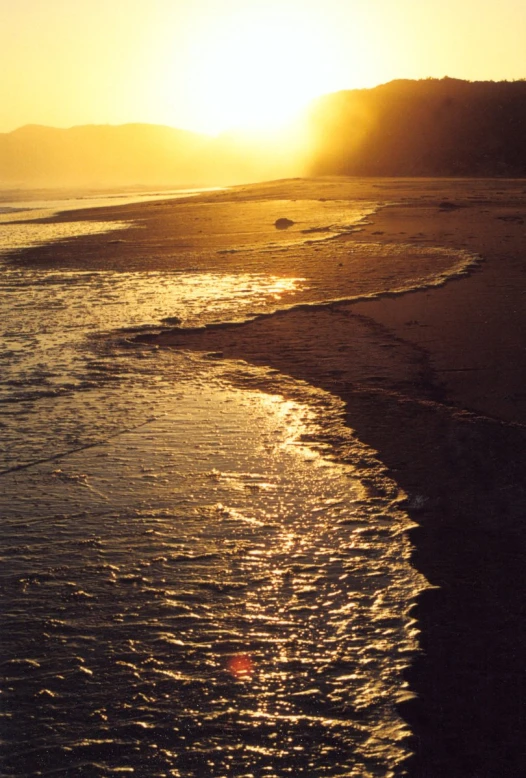 the sun shines brightly on a wet beach