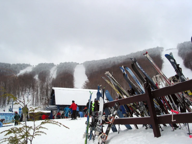 many skis sitting up against the top of a fence in the snow